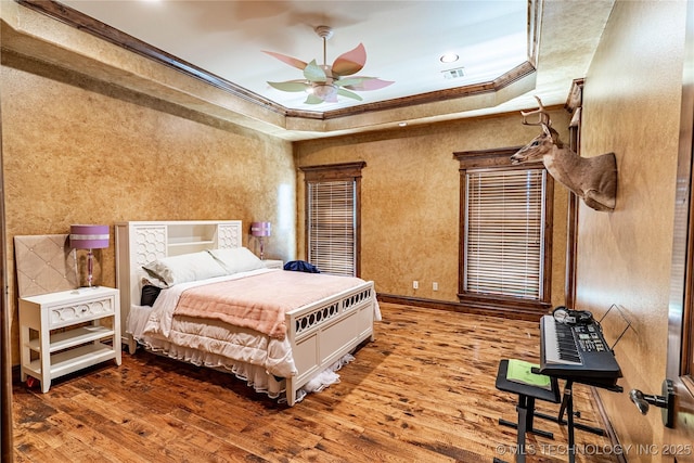 bedroom featuring visible vents, wood finished floors, ornamental molding, a tray ceiling, and recessed lighting