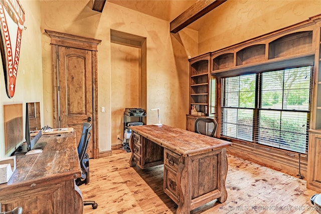 office area with beamed ceiling, a textured wall, and light wood finished floors