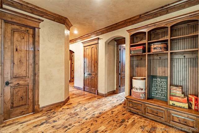 mudroom featuring wood-type flooring, arched walkways, baseboards, and ornamental molding