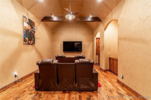 home theater room featuring arched walkways, ceiling fan, light wood finished floors, and lofted ceiling