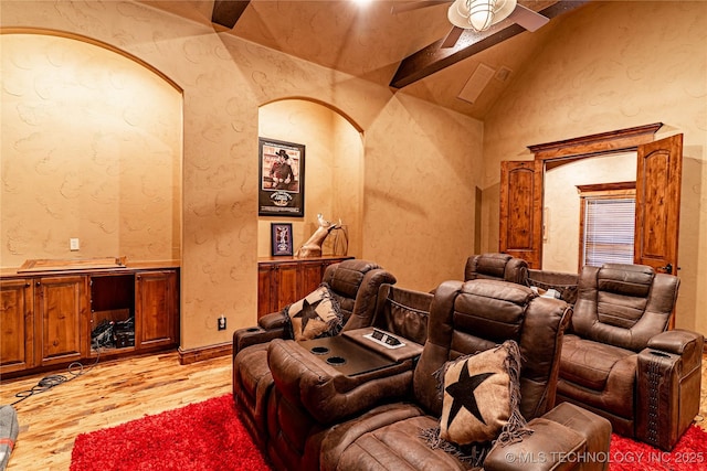 cinema with light wood-style floors, a ceiling fan, a textured wall, and lofted ceiling