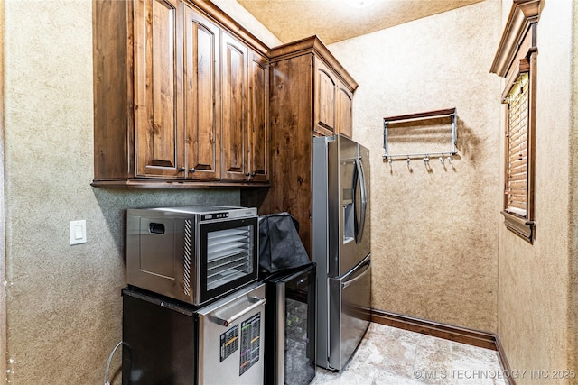 kitchen with stone finish flooring, wine cooler, a toaster, baseboards, and stainless steel fridge