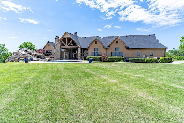 back of house featuring a lawn and a chimney