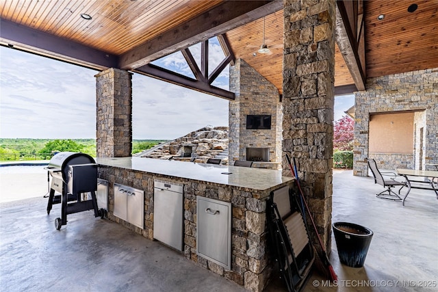 view of patio / terrace featuring an outdoor kitchen and an outdoor stone fireplace