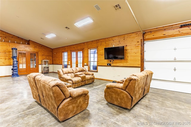 living area with visible vents, vaulted ceiling, wood walls, and finished concrete floors