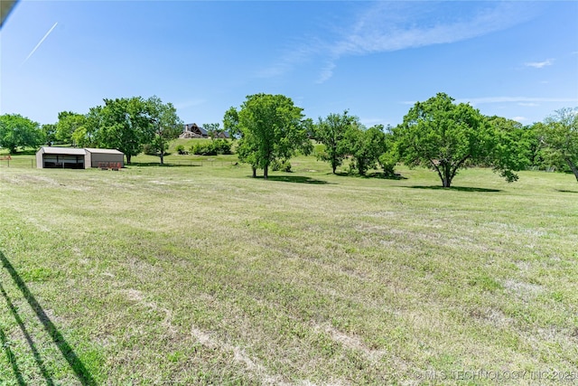 view of yard featuring a pole building, a detached carport, an outbuilding, and a rural view
