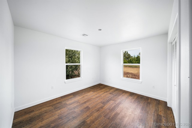 unfurnished bedroom featuring baseboards, visible vents, multiple windows, and dark wood finished floors