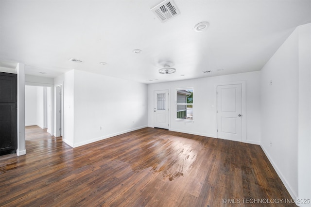 unfurnished living room with baseboards, visible vents, and dark wood finished floors