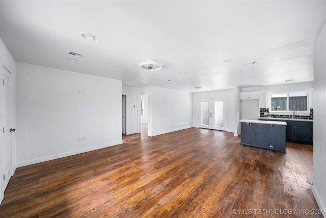 unfurnished living room with visible vents, a sink, dark wood-type flooring, and a wealth of natural light