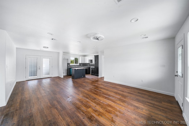 unfurnished living room featuring baseboards, dark wood-style floors, and visible vents