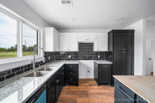 kitchen featuring white cabinets, light stone countertops, a sink, visible vents, and dark wood-style floors