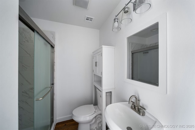 bathroom with a sink, a shower stall, toilet, and visible vents