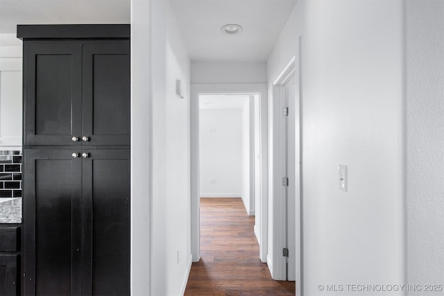 corridor featuring baseboards and dark wood-style flooring