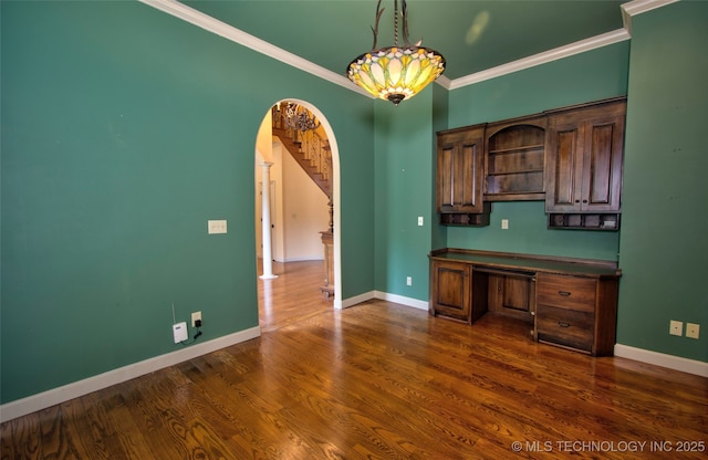 interior space featuring crown molding, dark countertops, arched walkways, baseboards, and dark wood-type flooring