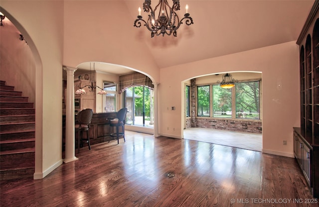 living area featuring dark wood-style floors, a chandelier, baseboards, and high vaulted ceiling