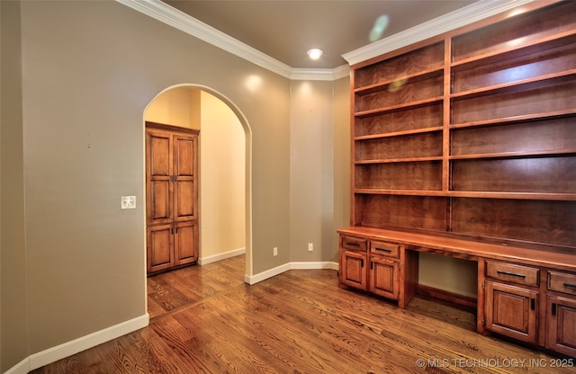 unfurnished office with baseboards, arched walkways, dark wood-style floors, and ornamental molding