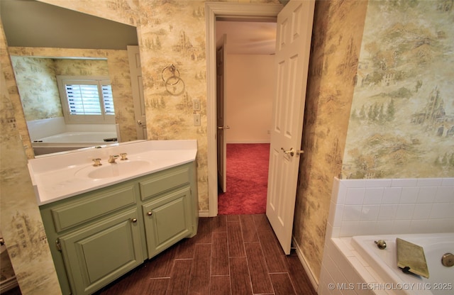full bath with wallpapered walls, a bath, and vanity