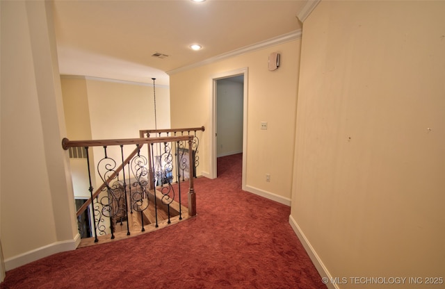 hallway featuring visible vents, ornamental molding, carpet, and an upstairs landing