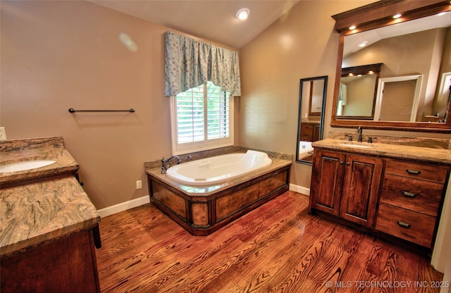 full bathroom with a sink, two vanities, wood finished floors, and lofted ceiling