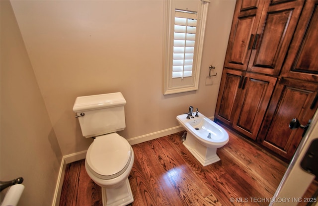 bathroom featuring a bidet, baseboards, toilet, and wood finished floors