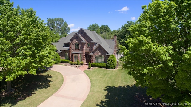view of front of home featuring a chimney, a front yard, and stone siding