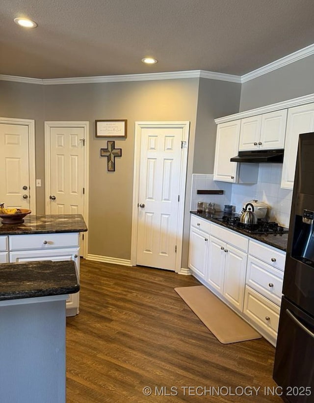 kitchen featuring white cabinets, dark wood-style flooring, under cabinet range hood, ornamental molding, and black appliances