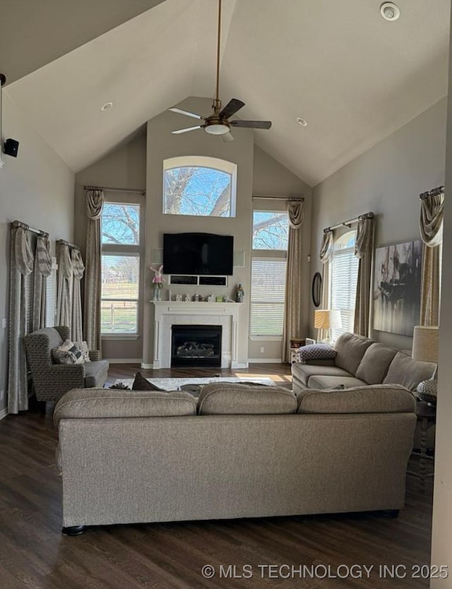 living area featuring dark wood-style flooring, ceiling fan, a wealth of natural light, and a fireplace