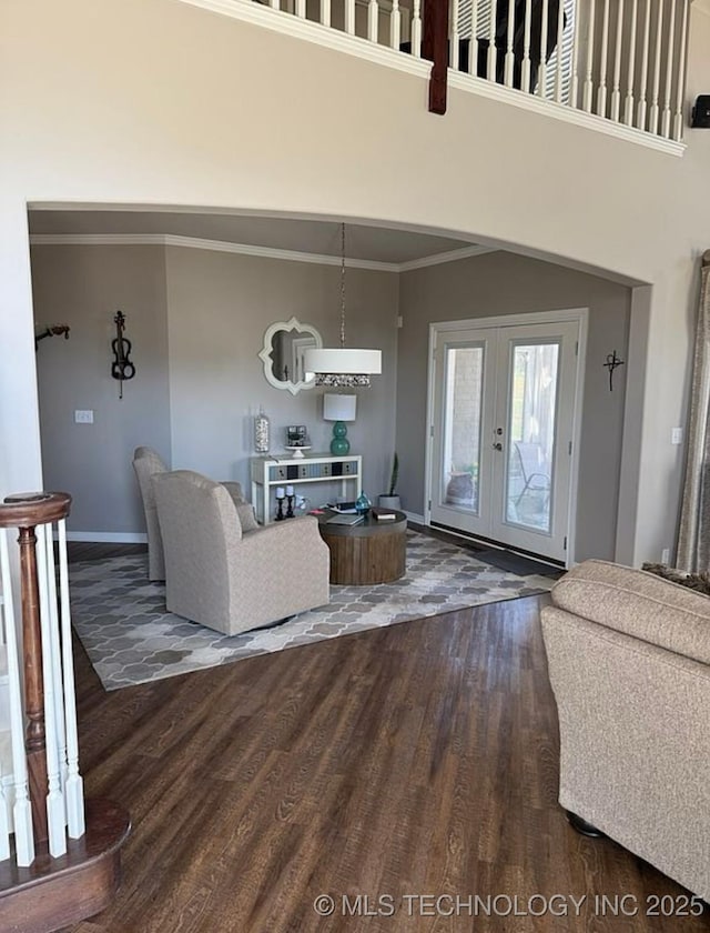 living room featuring french doors, wood finished floors, a high ceiling, baseboards, and ornamental molding