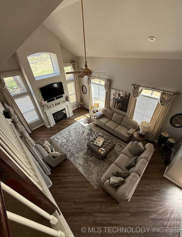 living room with wood finished floors, a fireplace, baseboards, ceiling fan, and vaulted ceiling
