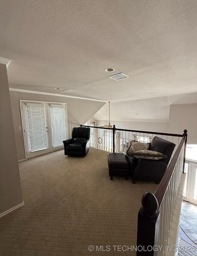 sitting room featuring visible vents, a textured ceiling, an upstairs landing, and carpet
