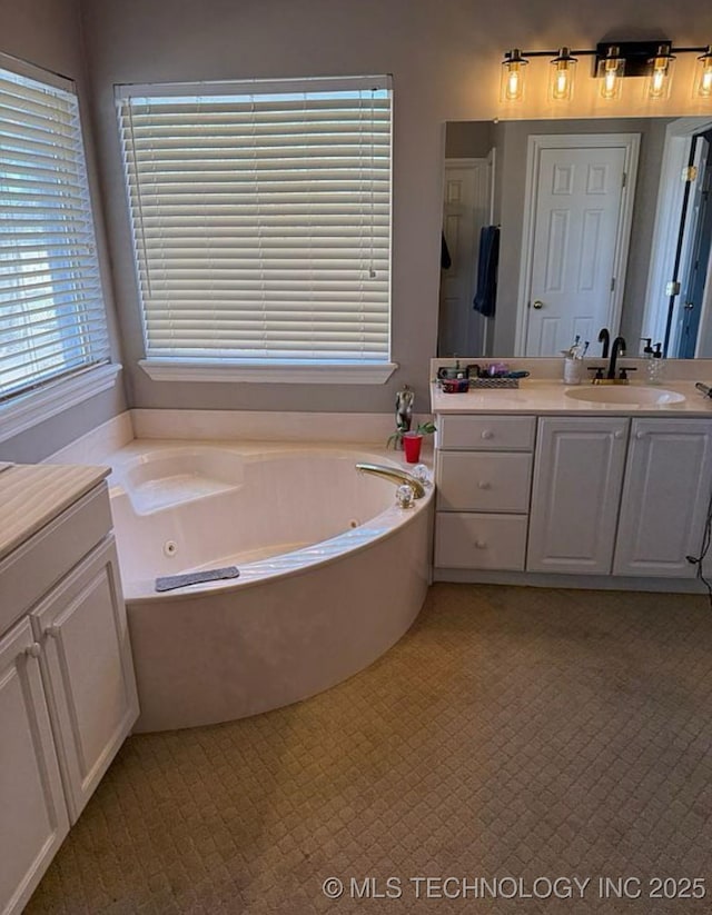 full bath featuring vanity, a healthy amount of sunlight, and a jetted tub