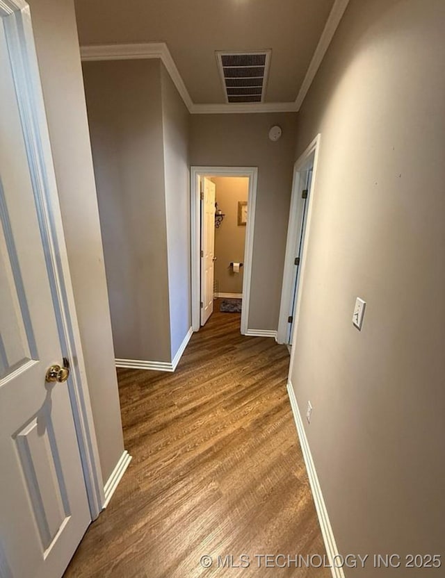 corridor with baseboards, visible vents, ornamental molding, and wood finished floors