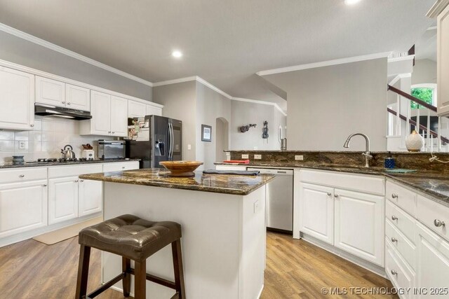 3401 N Narcissus Ave, Broken Arrow, OK 74012 - kitchen with dishwasher, black refrigerator with ice dispenser, under cabinet range hood, ornamental molding, and a kitchen breakfast bar