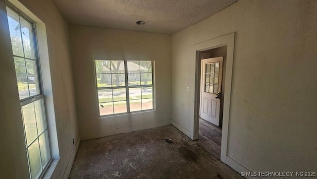 327 N G St, Muskogee, OK 74403 - spare room with a healthy amount of sunlight, baseboards, a textured ceiling, and visible vents