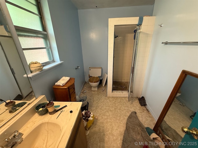 full bath featuring vanity, baseboards, toilet, and tiled shower
