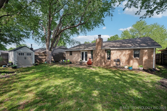 back of house featuring a patio, a fenced backyard, a chimney, a lawn, and a storage shed