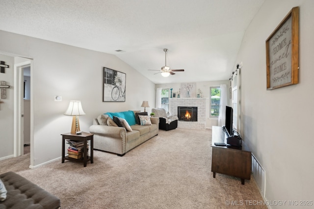 carpeted living room with lofted ceiling, a fireplace, baseboards, ceiling fan, and a barn door