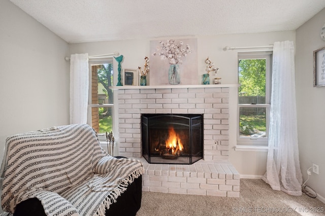 sitting room featuring a textured ceiling, carpet, a brick fireplace, and a wealth of natural light