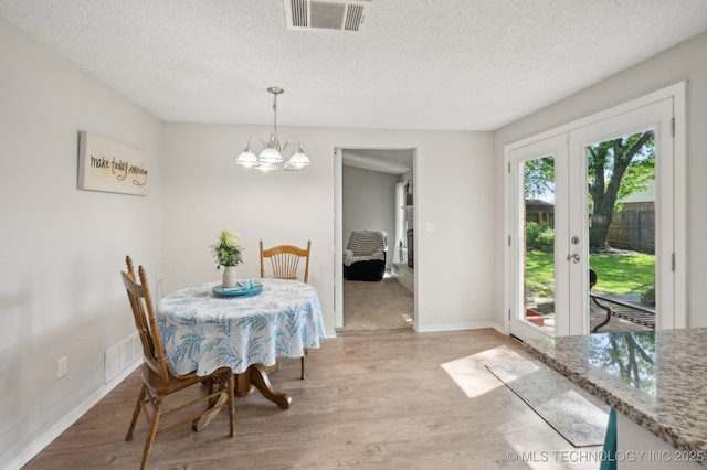 dining area with visible vents, a textured ceiling, and light wood-style floors