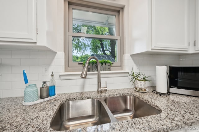 room details featuring a sink, backsplash, and white cabinetry