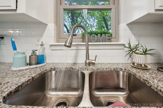 room details featuring a sink, white cabinets, light stone countertops, and tasteful backsplash
