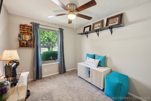 interior space featuring baseboards, a ceiling fan, a textured ceiling, and light carpet