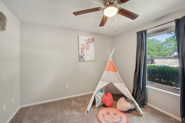 recreation room with carpet flooring, a ceiling fan, a textured ceiling, and baseboards