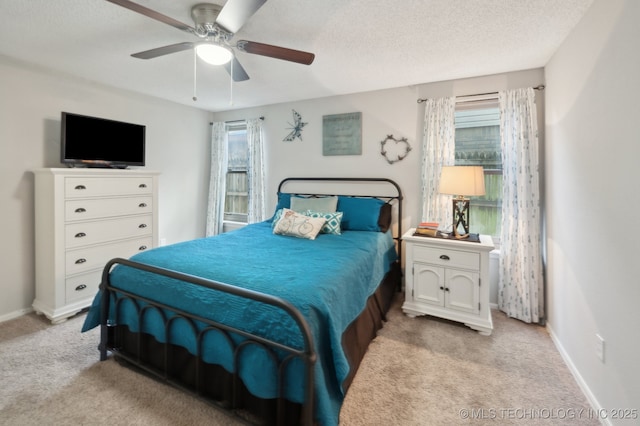bedroom featuring a ceiling fan, a textured ceiling, light carpet, and baseboards