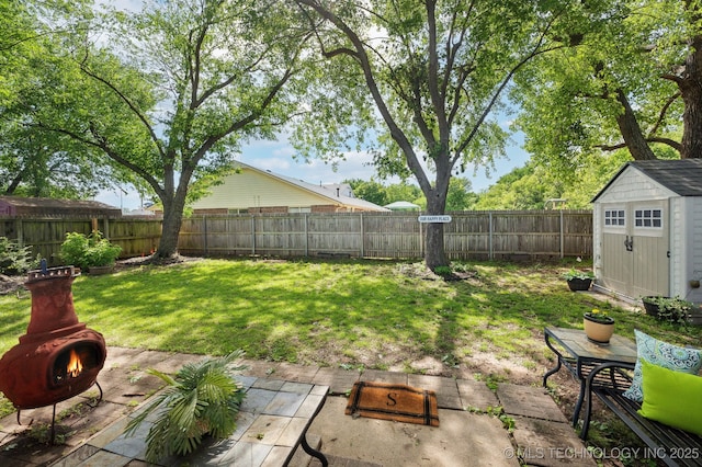 view of yard featuring a patio, a fenced backyard, an outdoor fire pit, and a storage unit