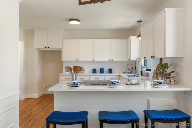 12415 N 75th E Ave, Collinsville, OK 74021 - kitchen featuring a peninsula, white cabinetry, tasteful backsplash, light countertops, and light wood-style floors