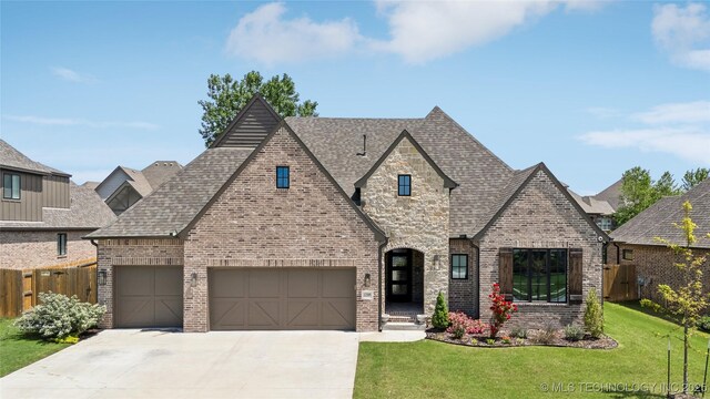 12509 S 102nd E Ave, Bixby, OK 74008 - french country home featuring a garage, fence, a front yard, brick siding, and concrete driveway
