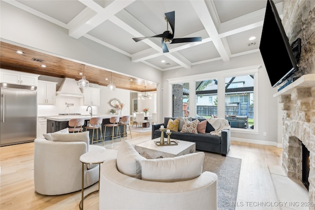 12509 S 102nd E Ave, Bixby, OK 74008 - living area featuring a stone fireplace, light wood-style floors, beam ceiling, and coffered ceiling