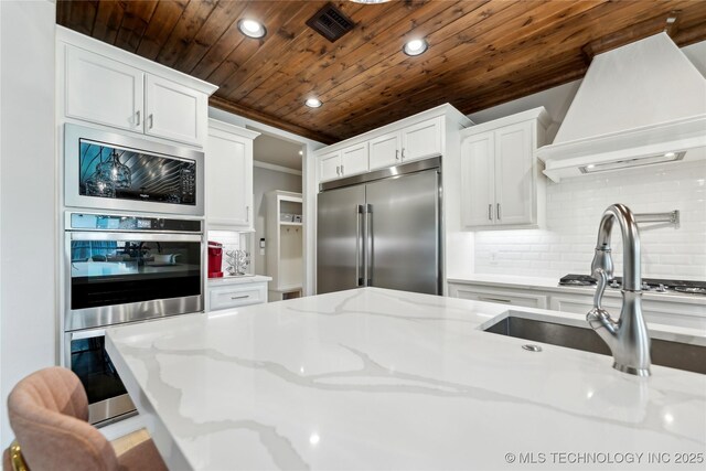 12509 S 102nd E Ave, Bixby, OK 74008 - kitchen with wood ceiling, tasteful backsplash, built in appliances, custom range hood, and white cabinetry
