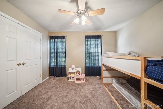 bedroom with a closet, baseboards, a ceiling fan, and carpet flooring